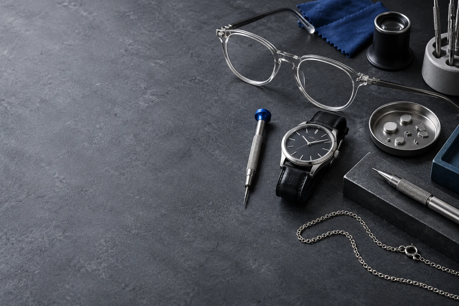 Illustrative slate repair bench with eyeglasses, watch, tools, battery tray and chain; not the merchant premises or customer property.